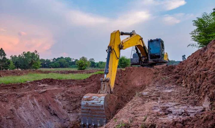 View of a backhoe digging a pit in the ground for rainwater