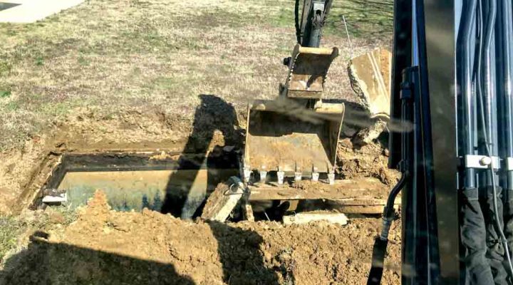backhoe excavator removing concrete debris on a lawn
